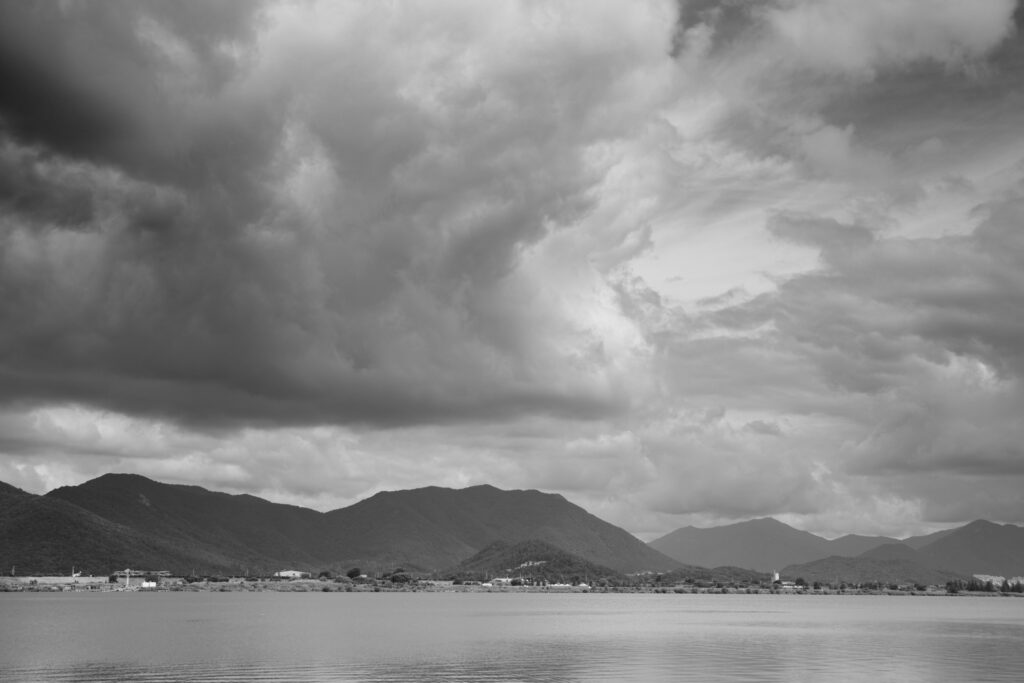 ダイナミックな形の雲と川のモノクロ写真