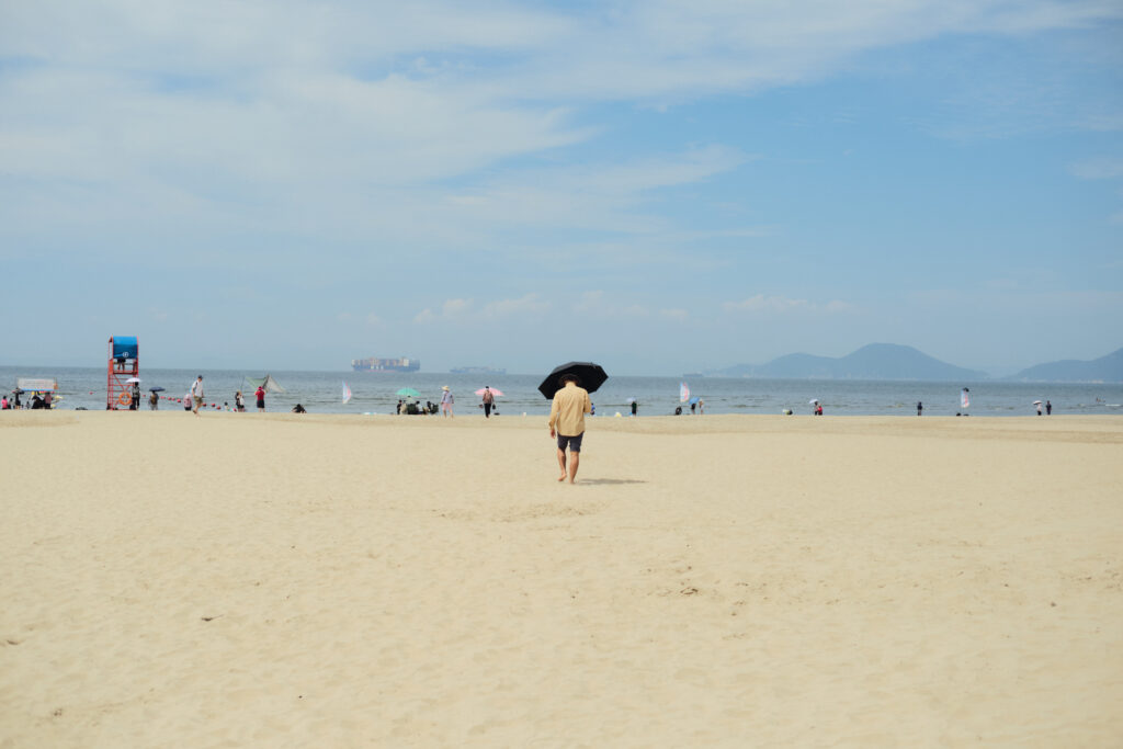 多大浦海水浴場で日傘をさして歩く男性